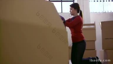 中年快乐的女人在搬家与盒子在新的平面和包装纸箱多利拍摄